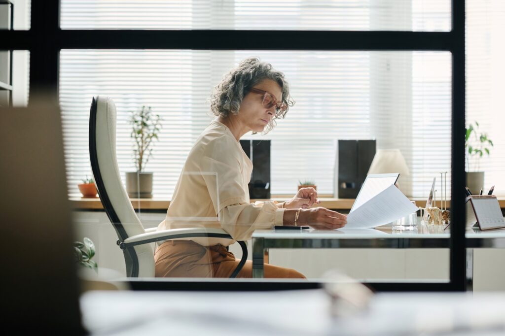 Serious mature female boss looking through financial document