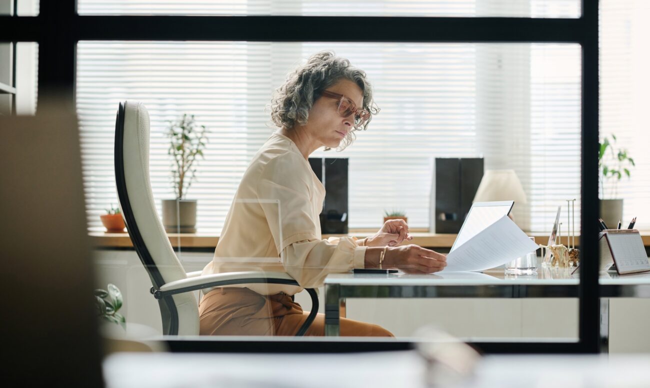 Serious mature female boss looking through financial document
