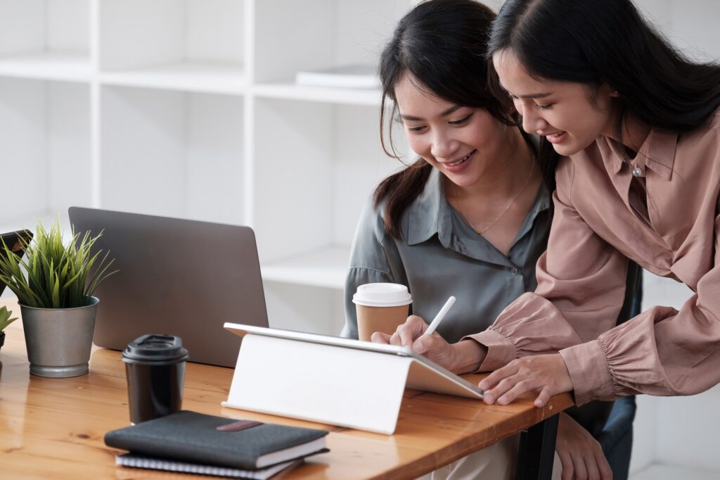 Two beautiful bussineswomen smiling happy. Working together speaking at the office.
