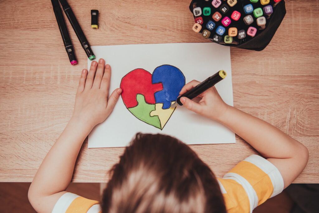World Autism Awareness day. Children's hand draws heart from multi-colored puzzles. Mental health