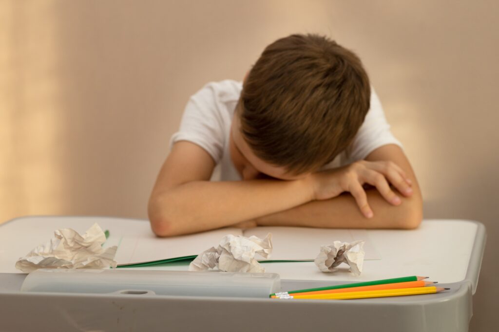 A 10-year-old schoolboy was doing his homework, very tired and sleeping at his desk