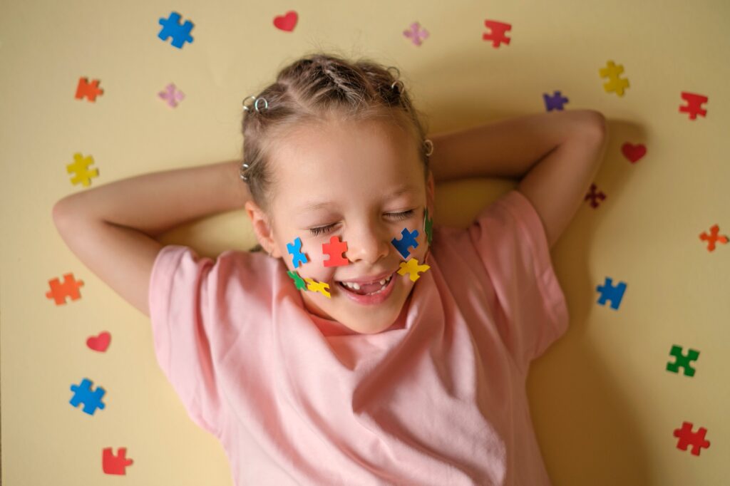 A funny laughing girl with no front teeth and multicolored puzzles pasted on cheeks.