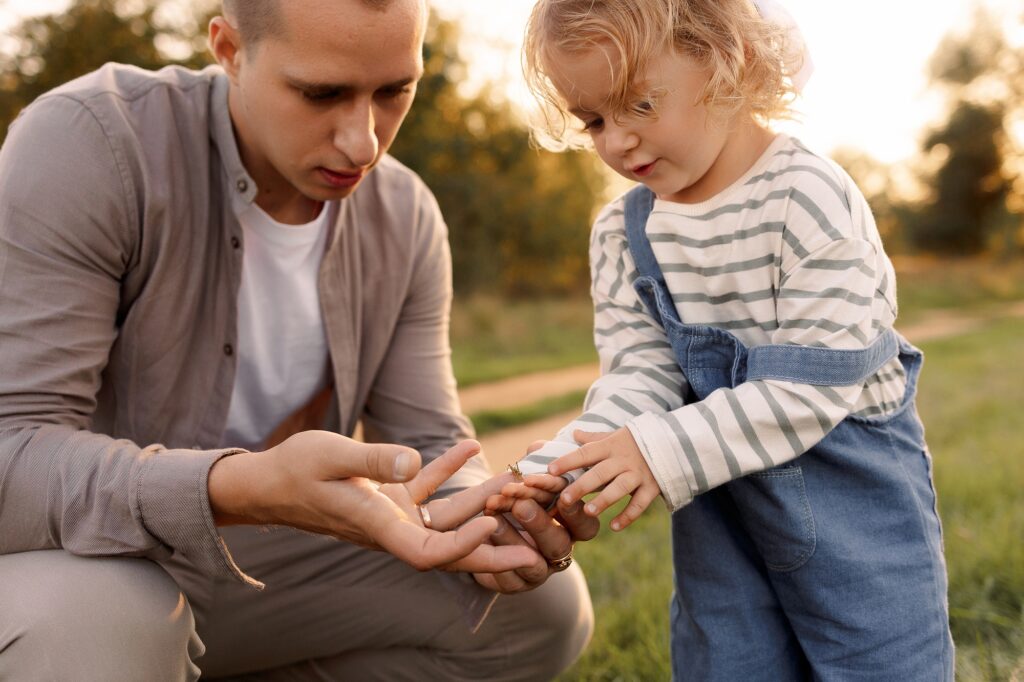 A man and a little girl are looking at a bug