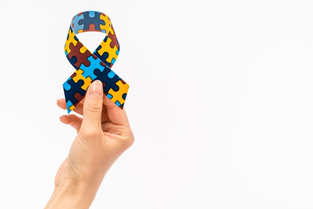 Cropped view of woman holding awareness ribbon isolated on white, autism concept