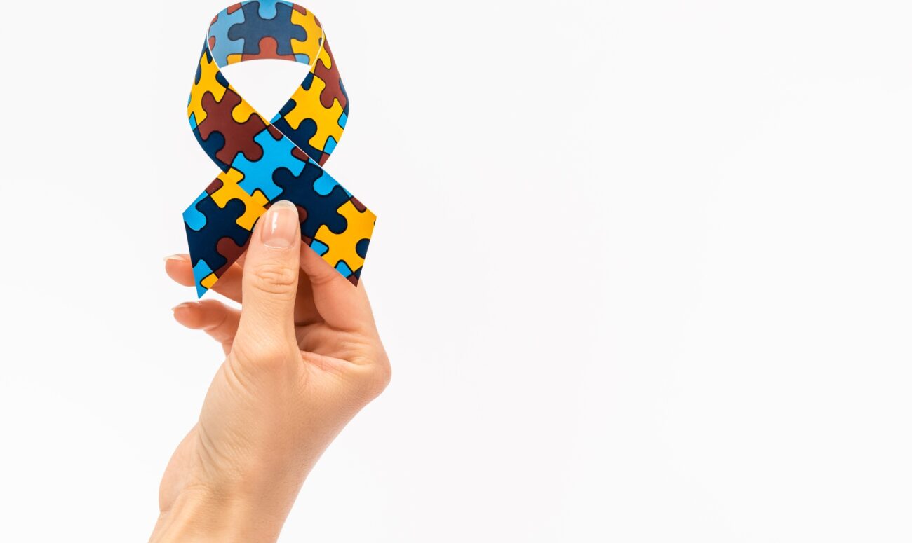 Cropped view of woman holding awareness ribbon isolated on white, autism concept
