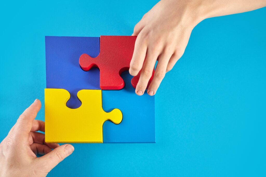 Father and autistic son hands holding jigsaw puzzle shape. World Autism Awareness Day