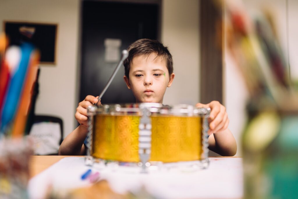 Autistic, Autism or Down Syndrome children boy is playing drum with his teacher.