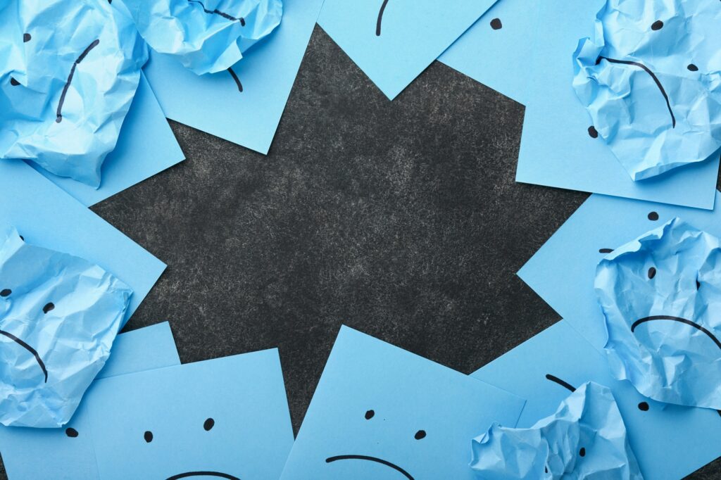 Blue crumpled sticky notes blank with drawing sad face on black background with copy space ready for