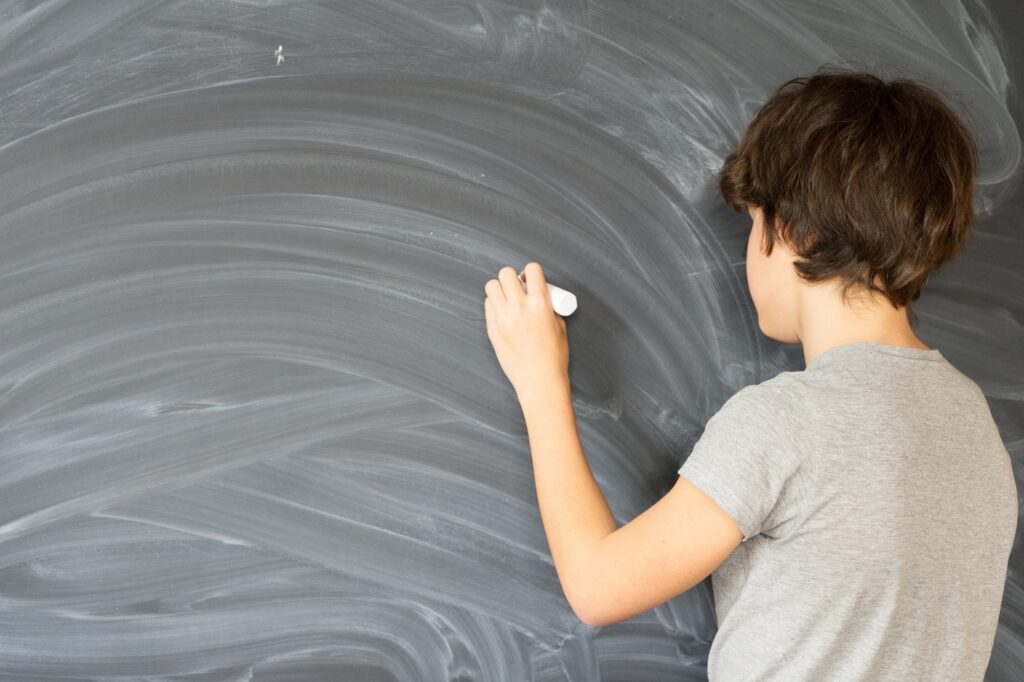 Boy writting on black board