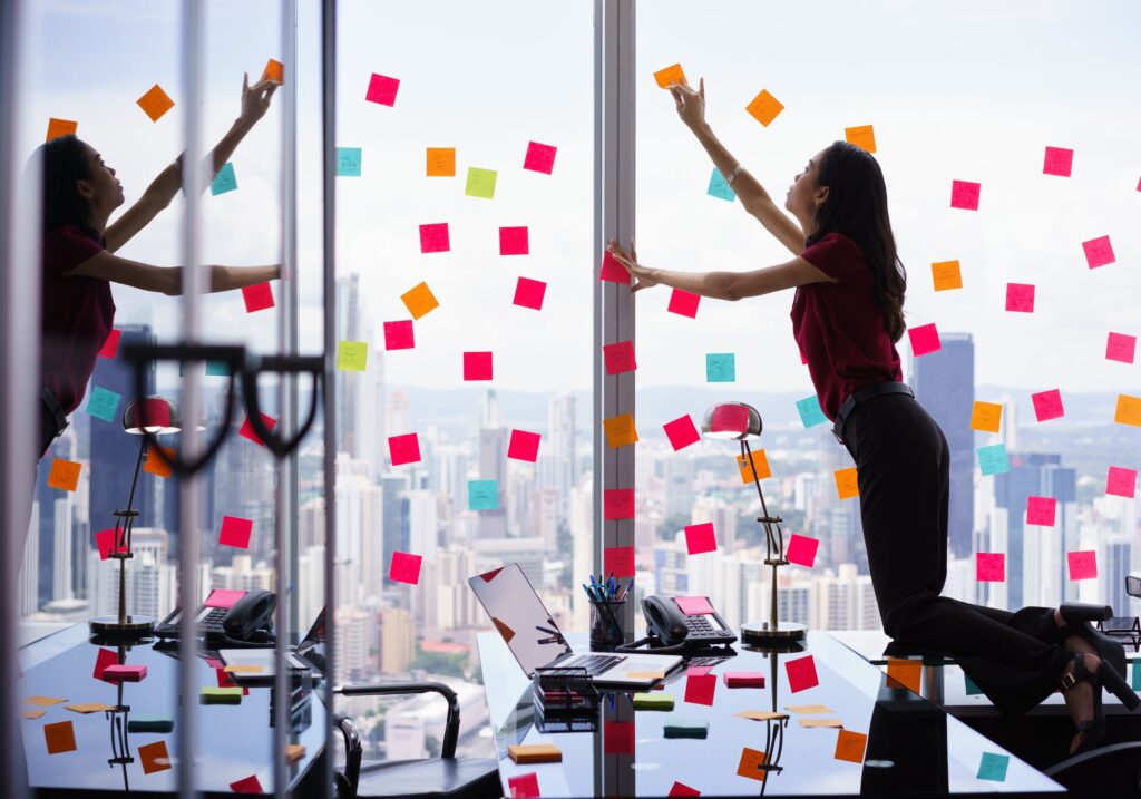 Busy Person Attaching Many Sticky Notes On Large Window