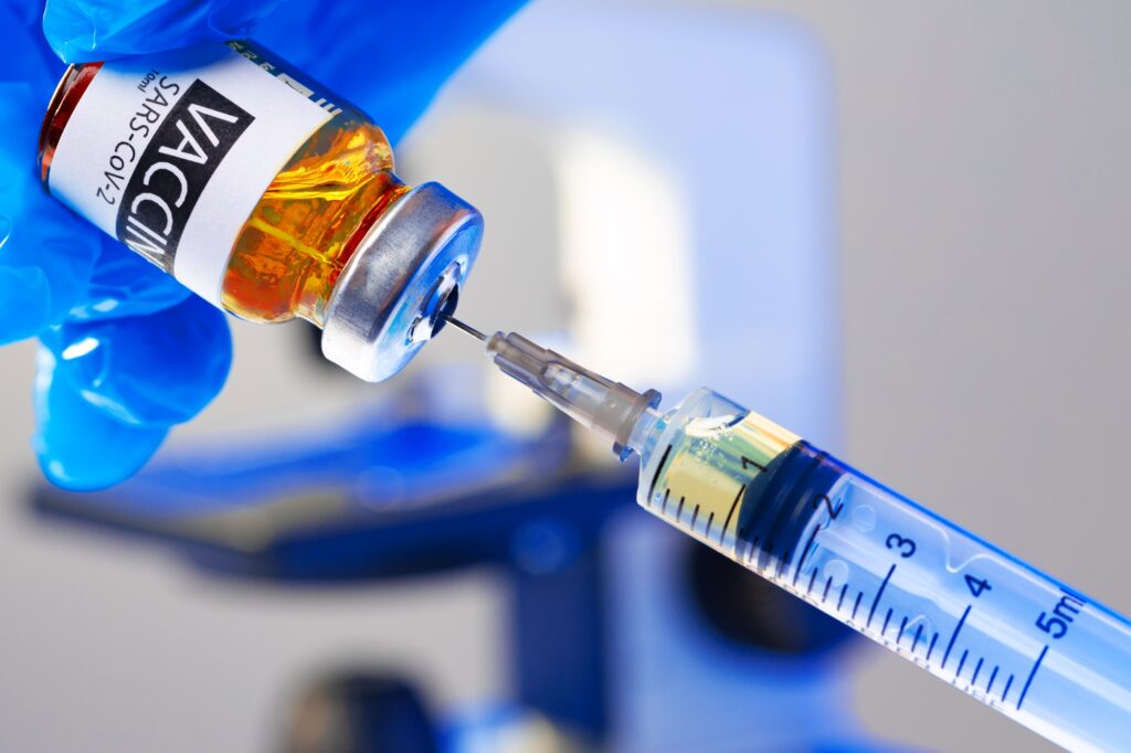 Covid-19 vaccine bottle with a syringe taking the vaccine from it