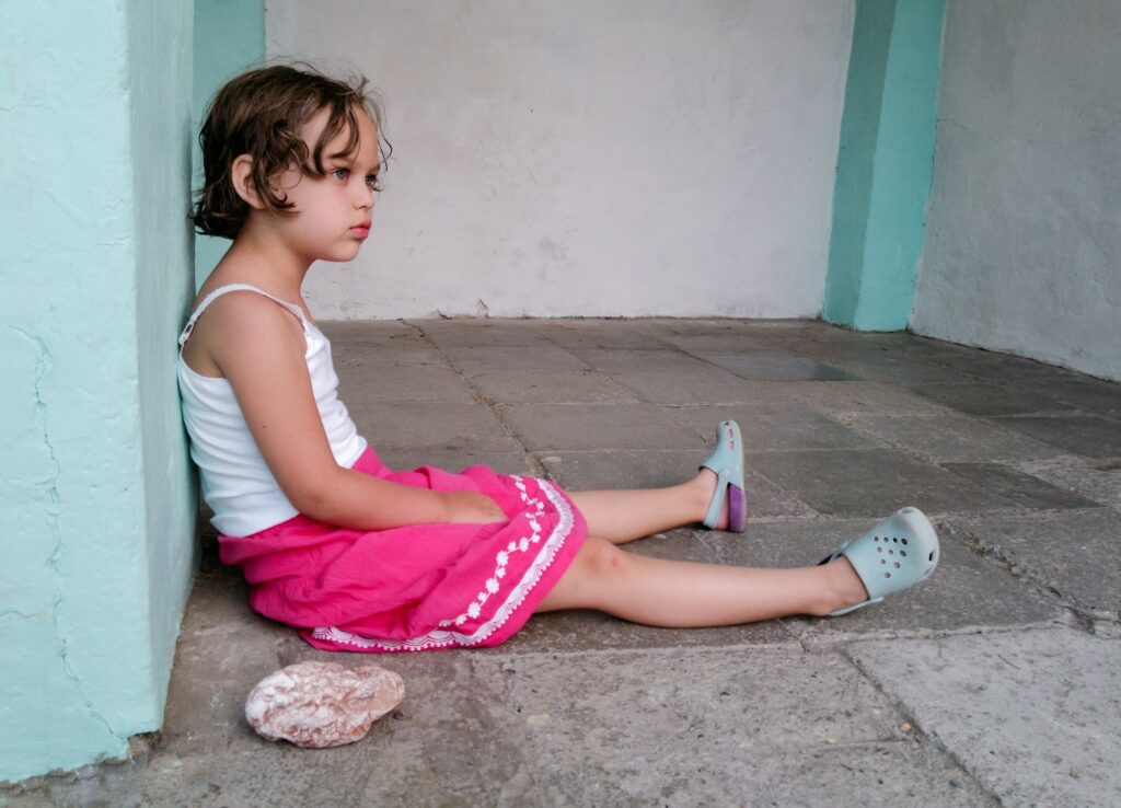 Cute angry girl is sitting on the floor. Concept of children behavior problem, hyperactivity - ADHD