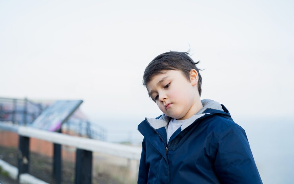 Dramatic portrait Lonely kid sad or bored face, Upset Young boy standing alone outside,