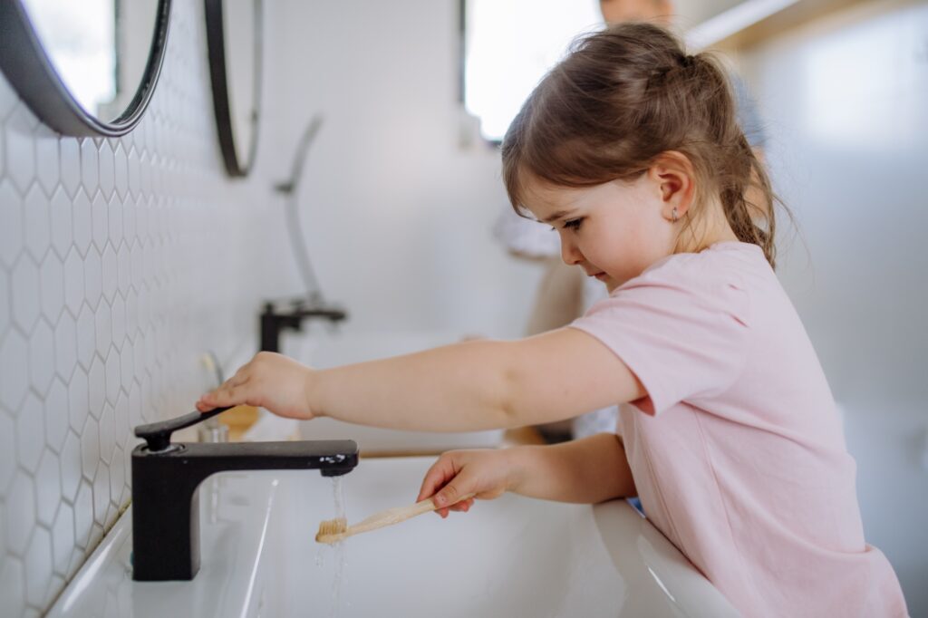 Little girl brushing her teeth in bathroom, morning routine concept.
