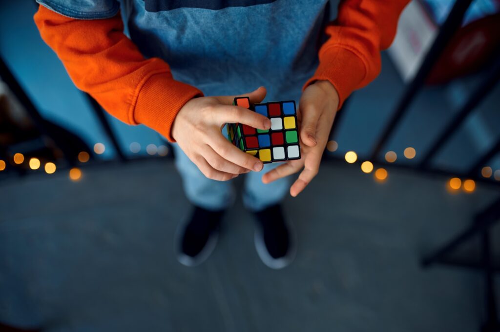 Male kid holds puzzle cube, focus on hand