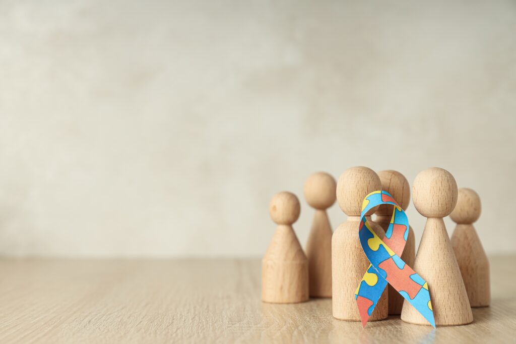 Ribbon with colorful puzzle pieces and wooden figures on light background, place for text