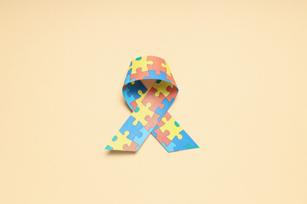 Ribbon with multi-colored puzzle pieces on a light background. World autism day concept