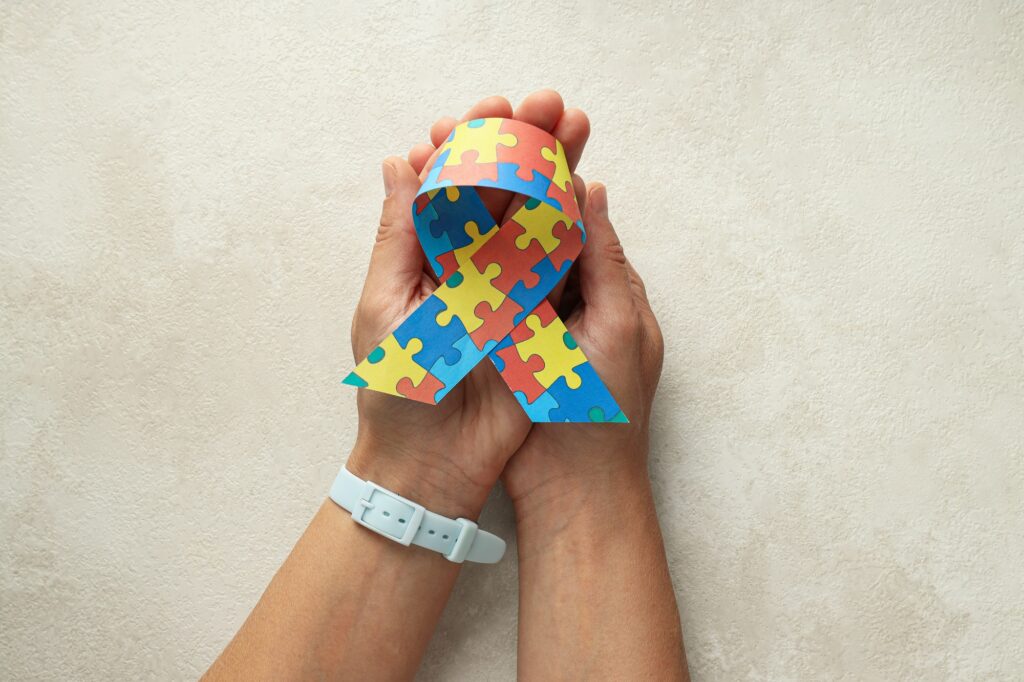 Ribbon with multi-colored puzzles on a light background. World autism day concept
