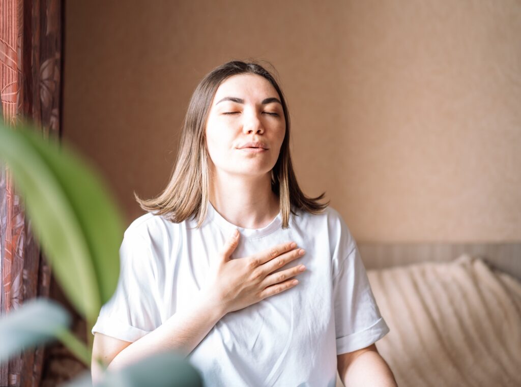 The lady put her hand to her chest and breathes deeply soothingly