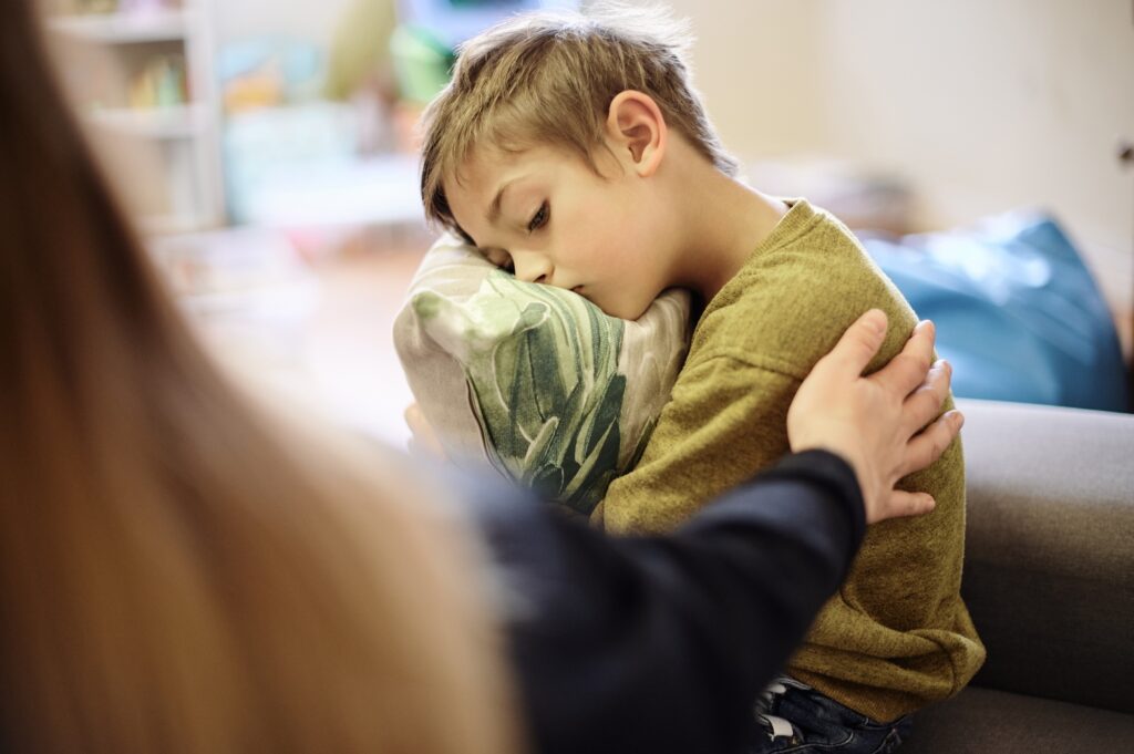 Autism, bullying and hand of mother with boy hugging pillow for comfort, compassion and empathy at
