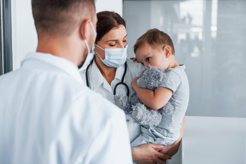 Little boy is in the clinic. Two doctors in white coats is in the hospital working together