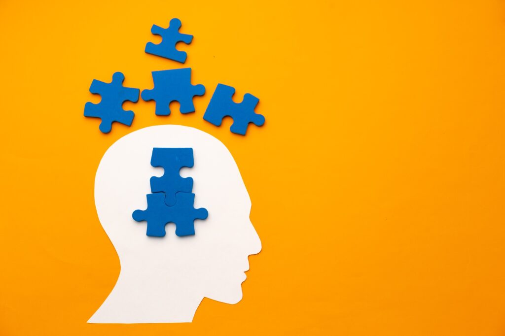 Papercut head silhouette with puzzle pieces on yellow background