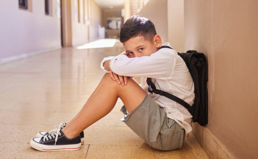 School child, bullying and sad student on ground for depression, anxiety and autism or learning pro