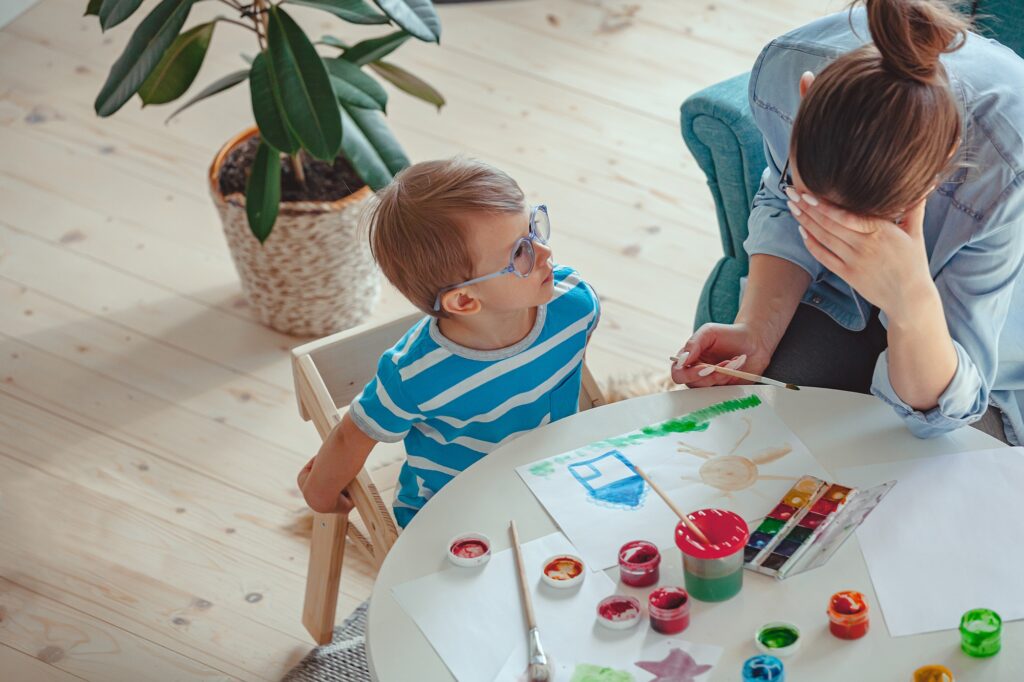 Tired Mother and child with autism paint watercolor together at