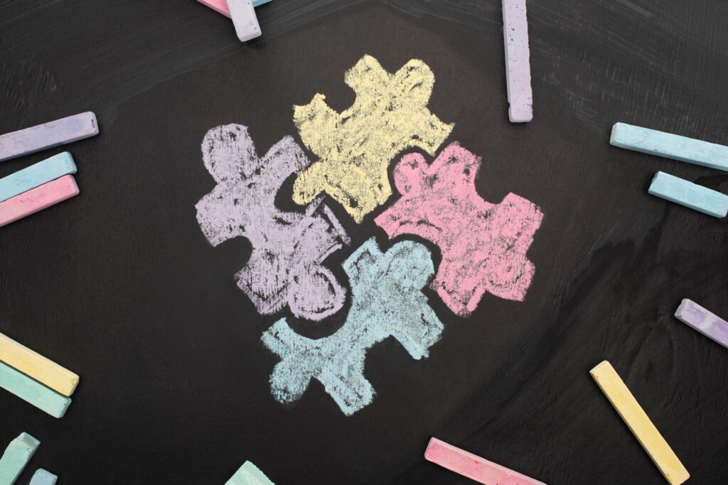 top view of chalks on blackboard with puzzle drawing for World Autism Awareness Day