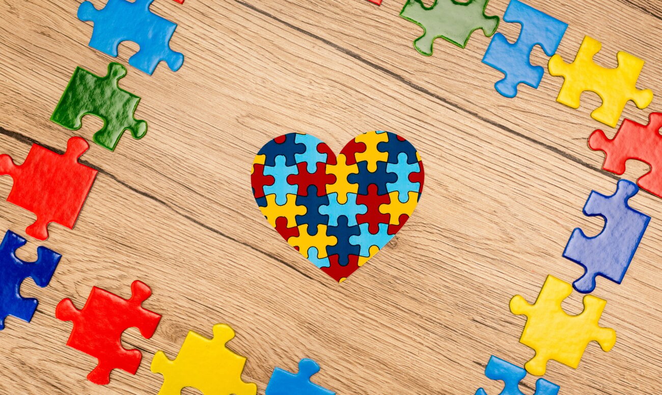 Top view of puzzle heart on wooden background, autism concept